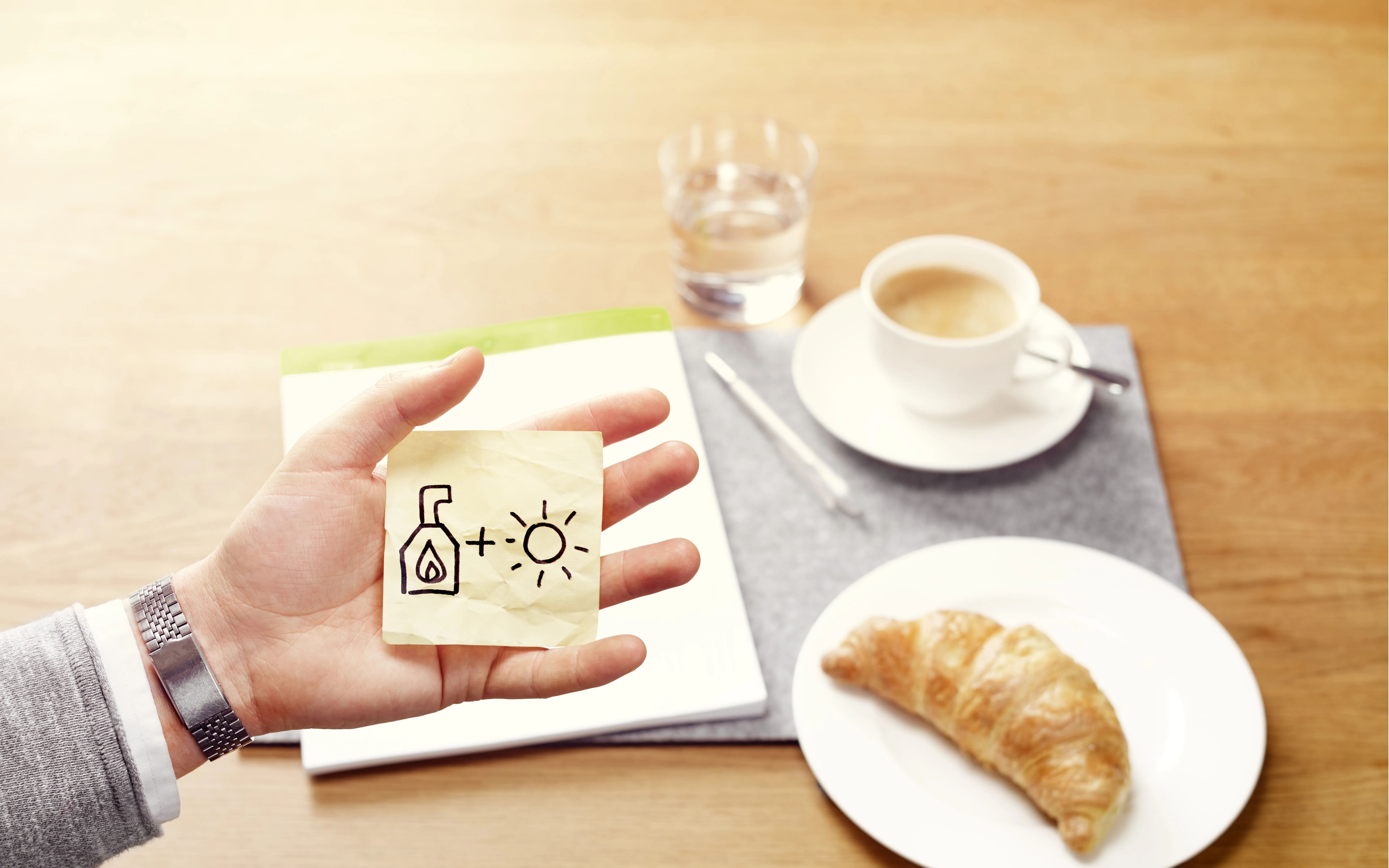 Eine Hand mit Skizze vor Frühstückstisch.