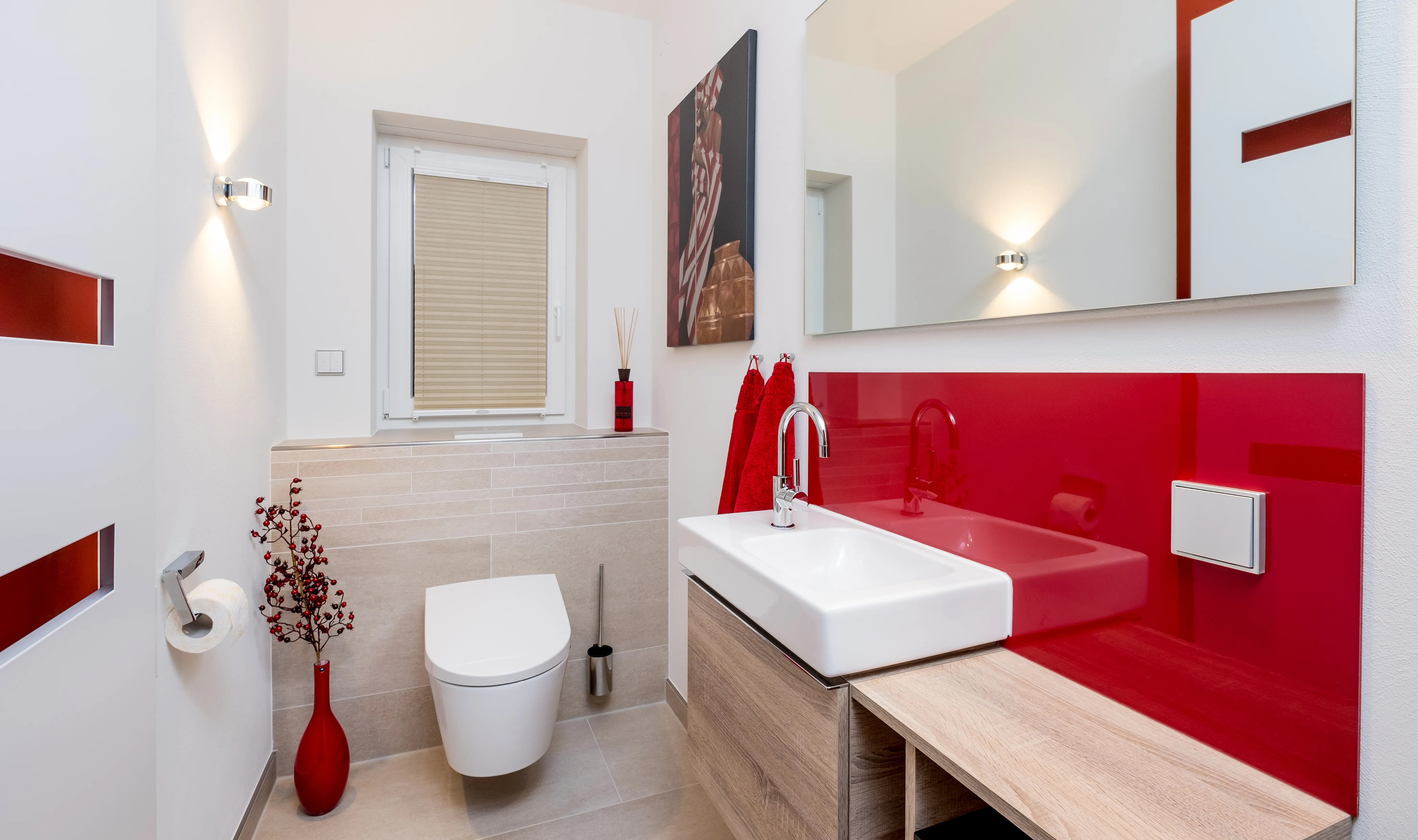 Detailansicht des Waschtisches mit Armatur vor roter Glasrückwand.