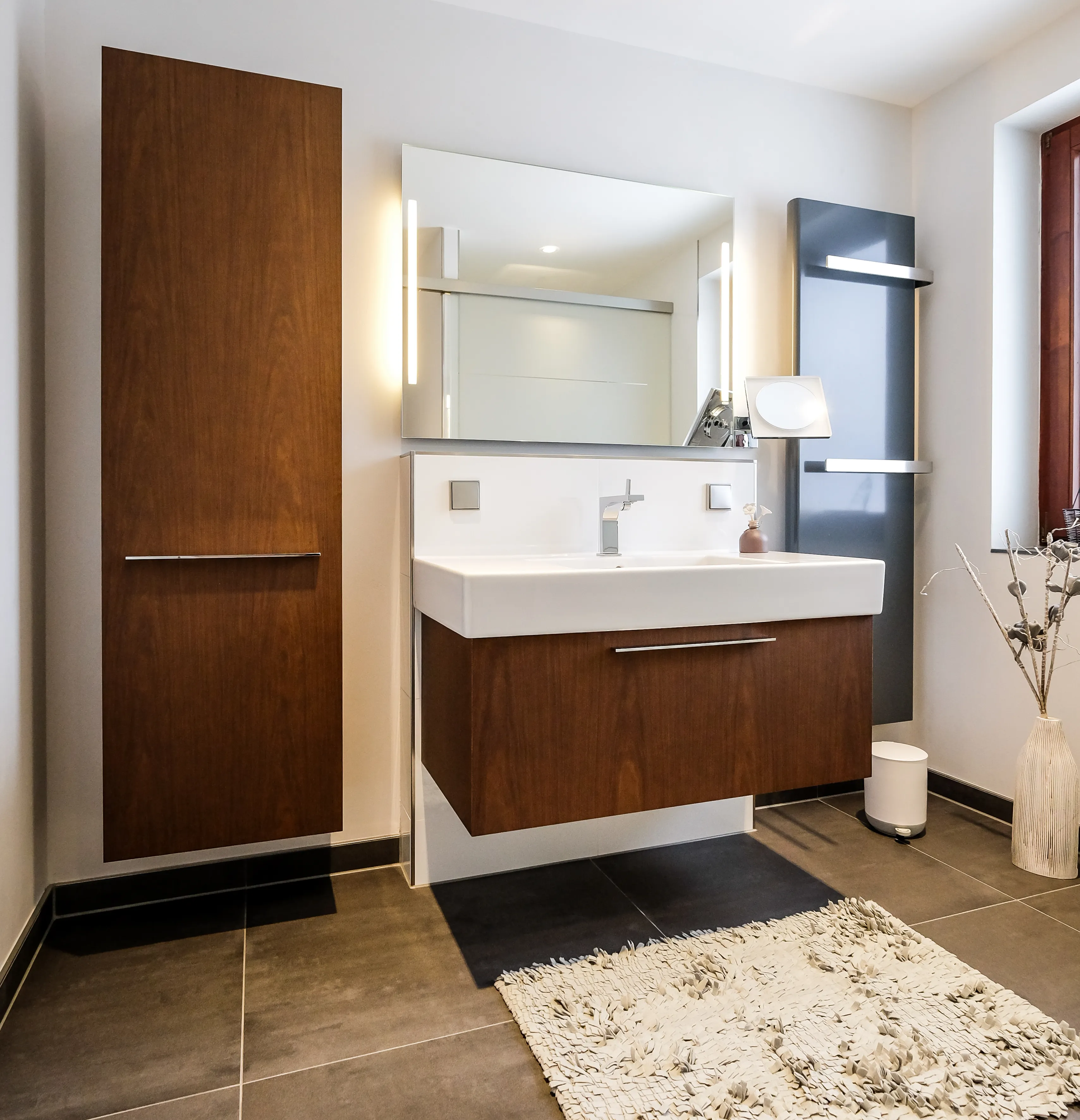 Modernes Badezimmer mit Waschtisch, Holzbadmöbeln, LED-Spiegel und Handtuchheizkörper.