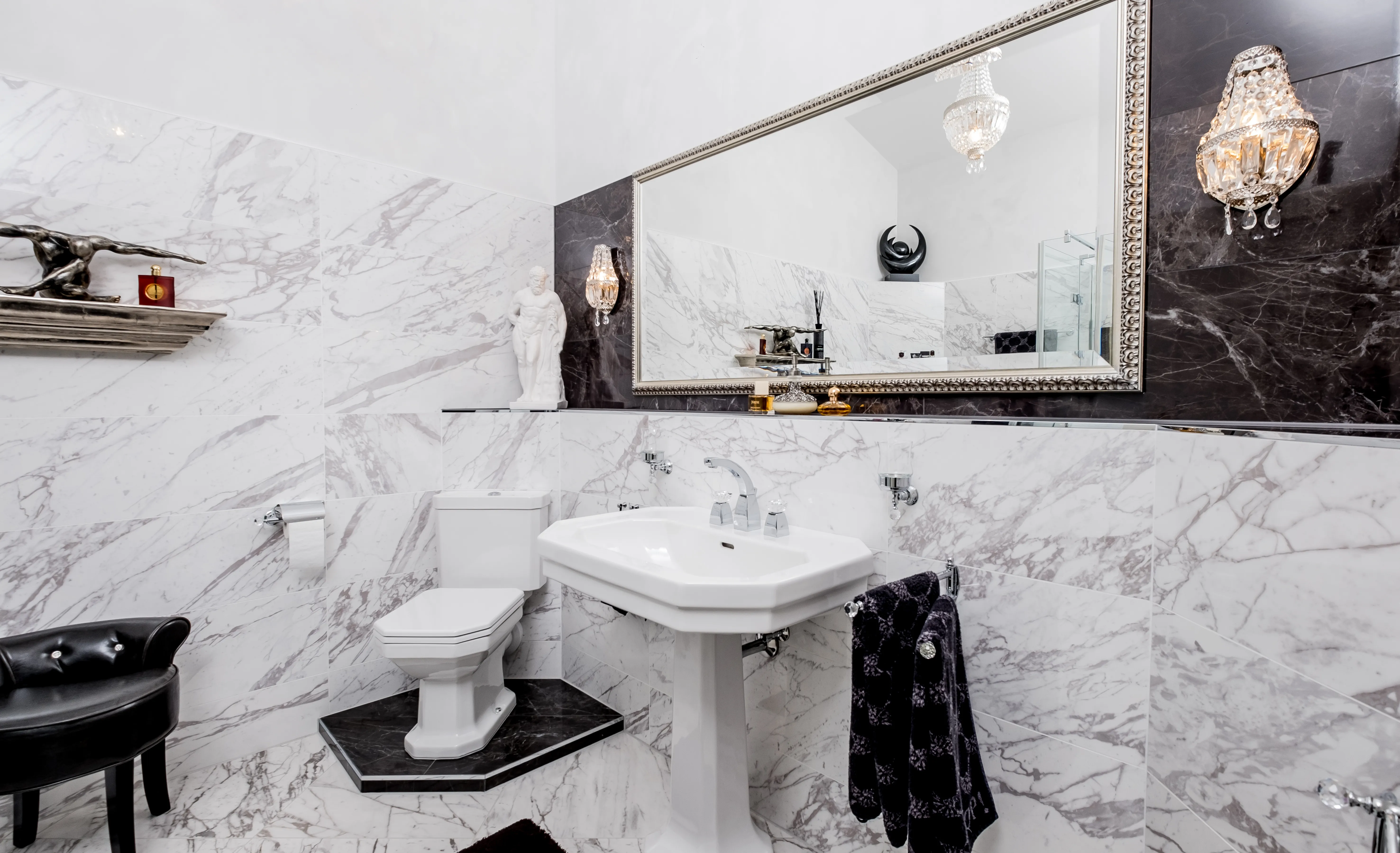 Klassisches Badezimmer mit Marmorfliessen, Waschtisch und großem Wandspiegel.