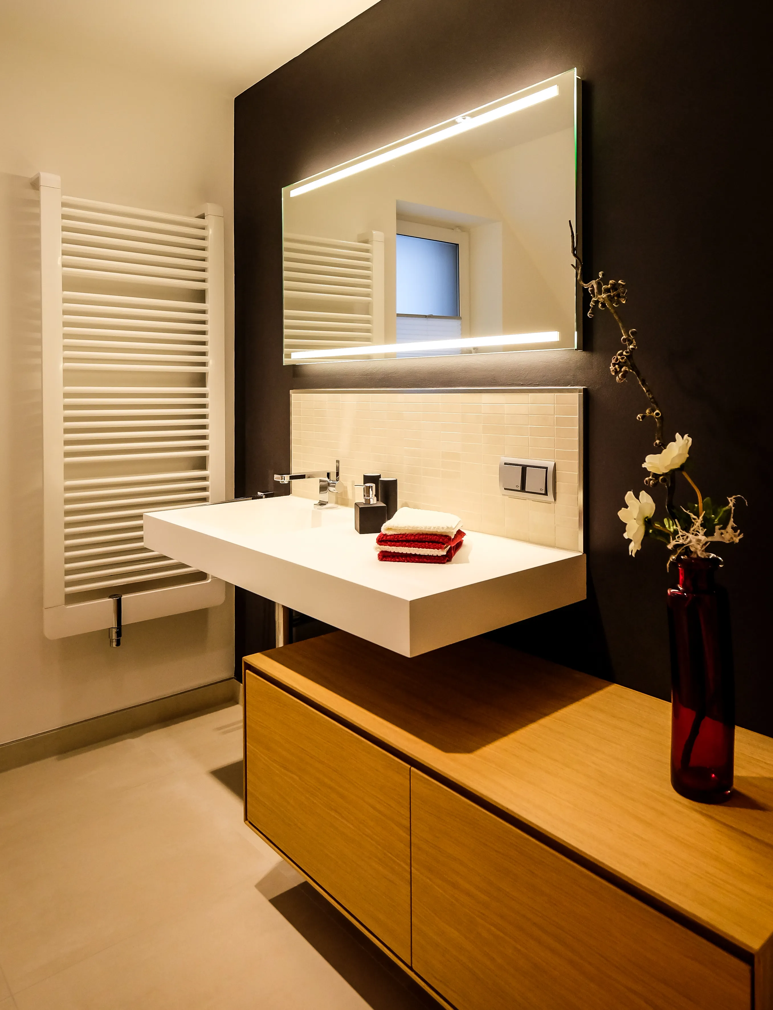 Detailansicht Waschtischanlage mit schwebendem Waschbecken, Armatur und beleuchtetem Spiegel.