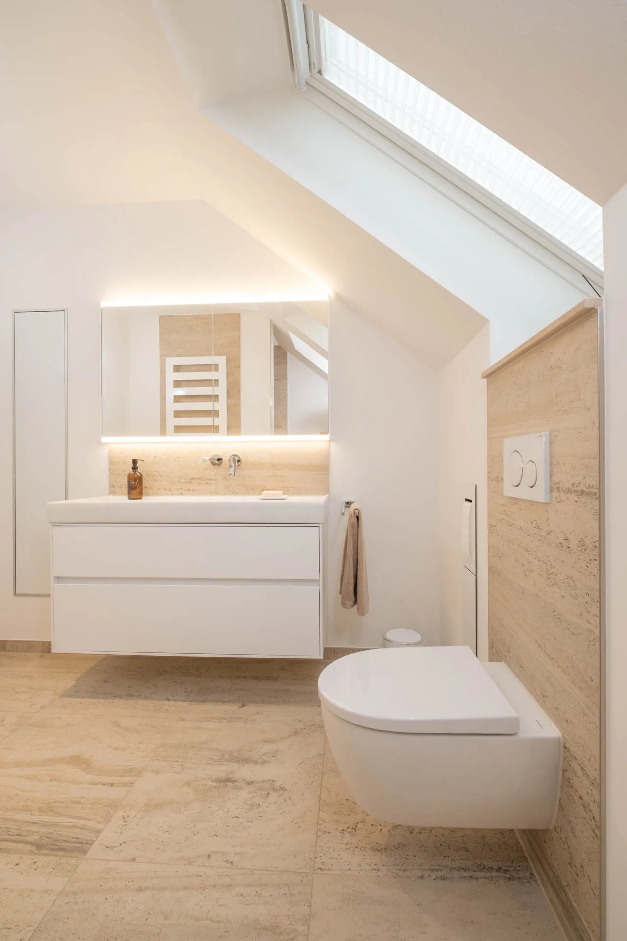 Dachgeschoss-Badezimmer mit schwebendem Waschtisch, Wand-WC und indirekter LED-Beleuchtung.