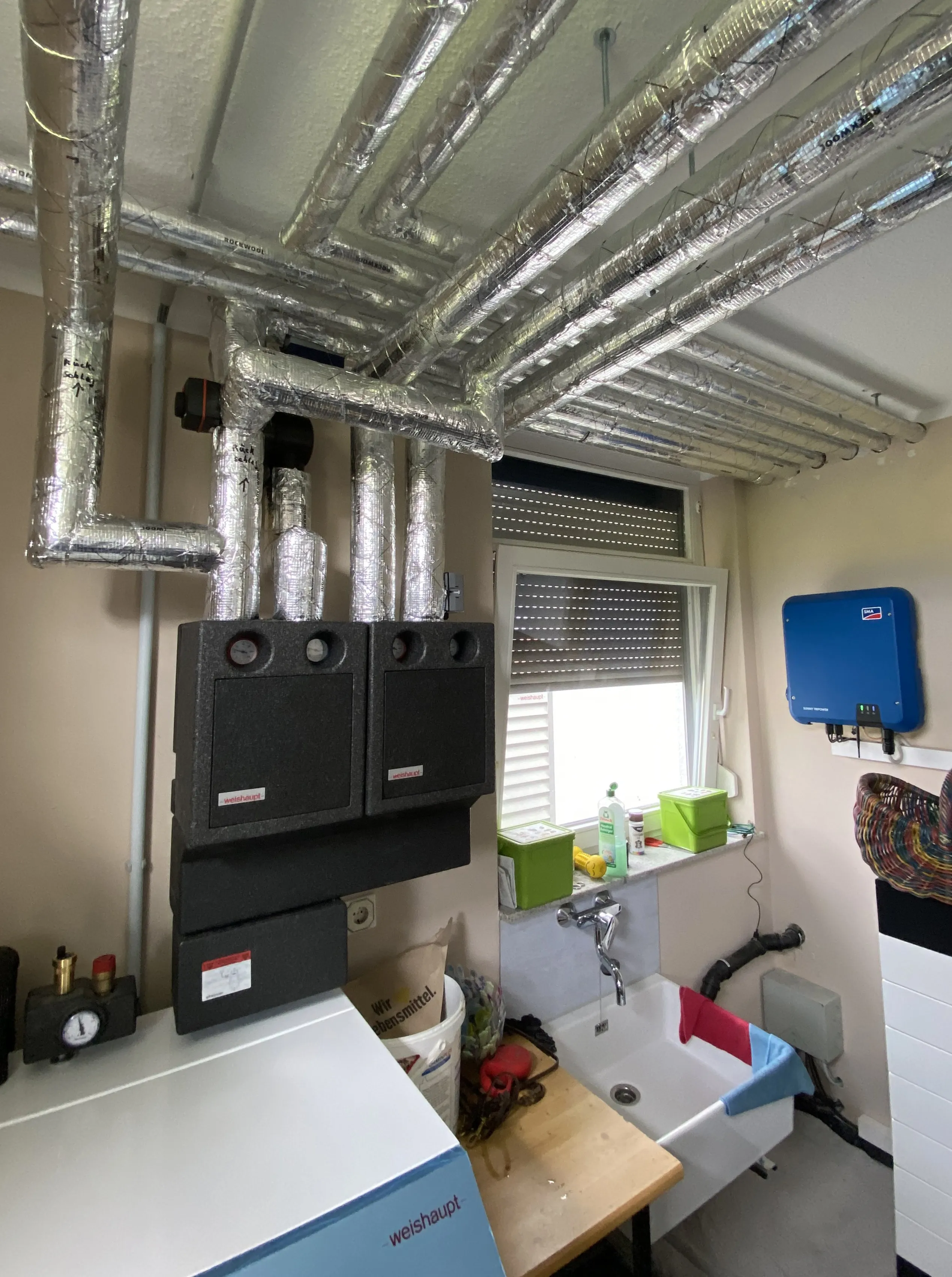 Heizungsverteiler und komplexes Rohrsystem einer Wärmepumpenanlage im Technikraum.