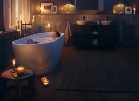 Badewanne in stilvollem Badezimmer mit warmem Kerzenschein und Holzfußboden.