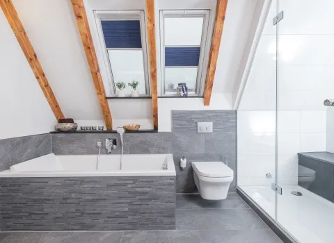 Bad mit Badewanne, wandhängendem WC und bodengleicher Dusche mit Glasabtrennung.