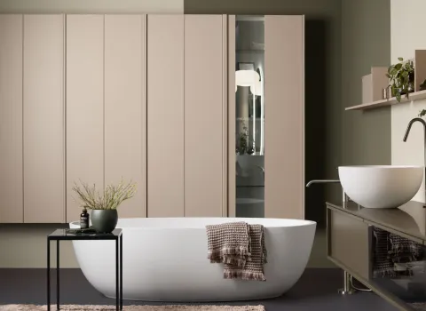 Sanftes, wohnliches Badezimmer von Stocco mit freistehender Badewanne, beigefarbenen Schränken und Aufsatzbecken auf Glasfront-Unterschrank.