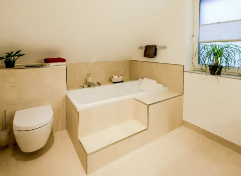 Badewanne mit integrierter Stufe und seitlicher Ablage in hellem Badezimmer.