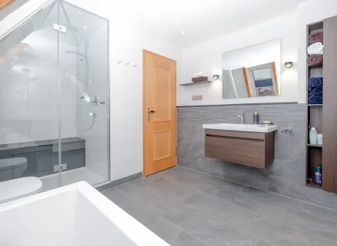 Modernes Bad mit Glasdusche, Waschtisch und Holztür.