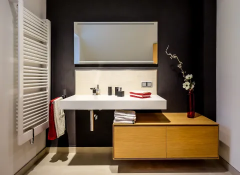 Modernes Badezimmer mit weißem Waschtisch, Holz-Unterschrank, LED-Spiegel und Handtuchheizkörper.