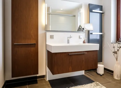 Modernes Badezimmer mit Waschtisch, Holzbadmöbeln, LED-Spiegel und Handtuchheizkörper.