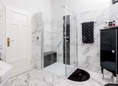 Moderne Glasdusche in Marmorbad mit schwarzem Badschrank.