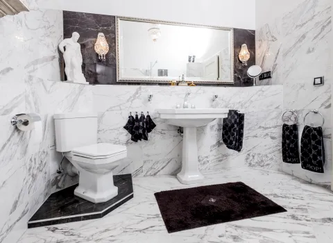 Badezimmer mit WC, Standwaschbecken und Marmorwandfliesen.