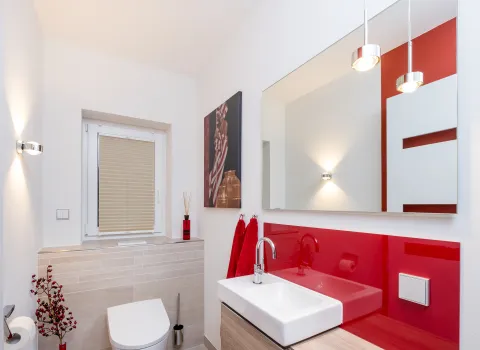 Wandhängendes WC und moderner Waschtisch mit Holzablage in hellem Badezimmer.