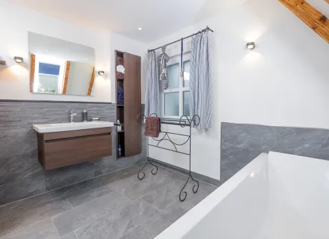 Waschtisch mit Unterschrank, großem Spiegel und Handtuchregal im modernen Bad.