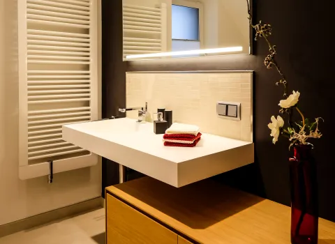 Detailansicht Waschtischanlage mit schwebendem Waschbecken, Armatur und beleuchtetem Spiegel.