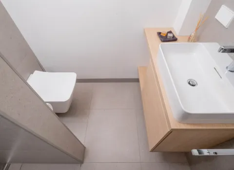 Detailansicht eines Waschbeckens mit Holzunterschrank und moderner Armatur.