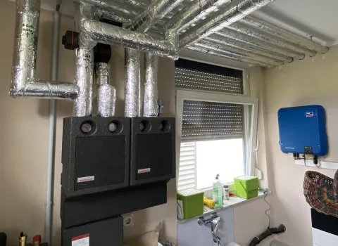 Heizungsverteiler und komplexes Rohrsystem einer Wärmepumpenanlage im Technikraum.