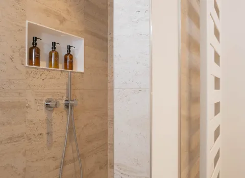 Detailaufnahme einer modernen Badezimmer-Dusche mit Naturstein und integrierter Wandnische.