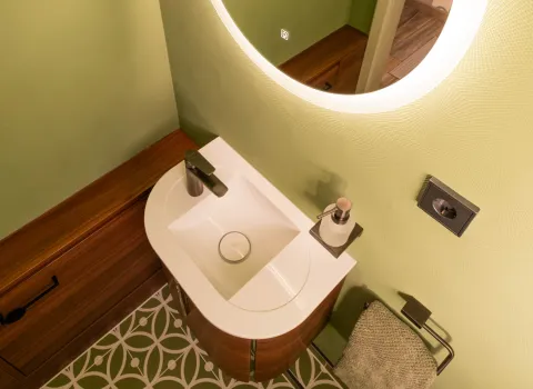 Draufsicht auf Waschbecken mit grünem Fliesenboden im modernen Gäste-WC.