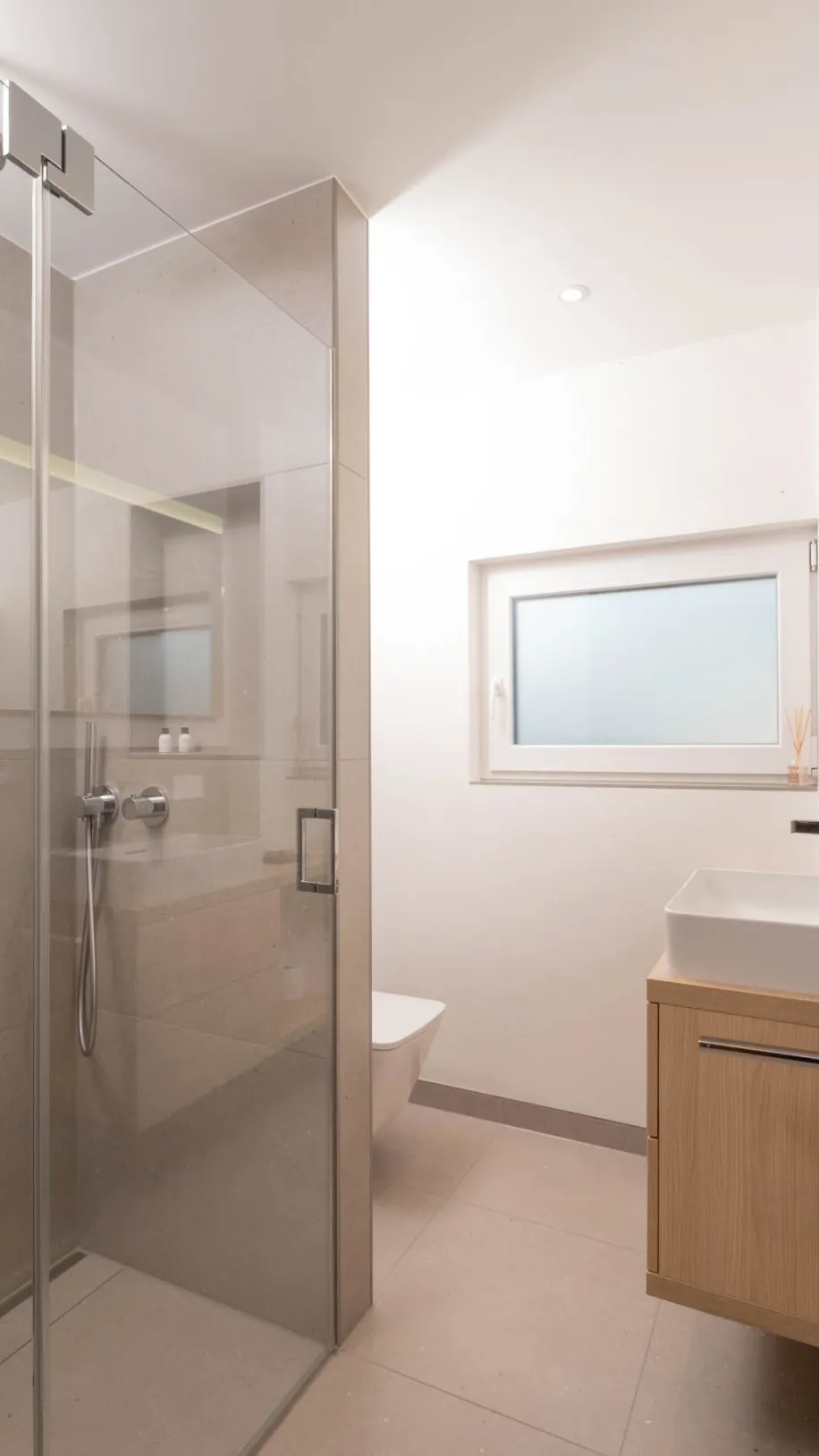 Kompaktes Badezimmer mit Walk-in-Dusche, Fenster und wandhängendem Holzwaschtisch.