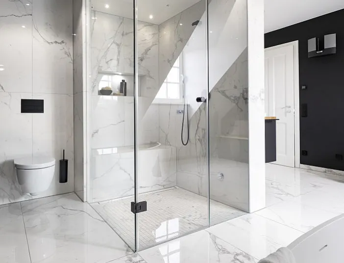 Ein modernes Badezimmer mit großformatigen Marmorfliesen zeigt eine luxuriöse Dampfdusche mit gläserner Kabine.